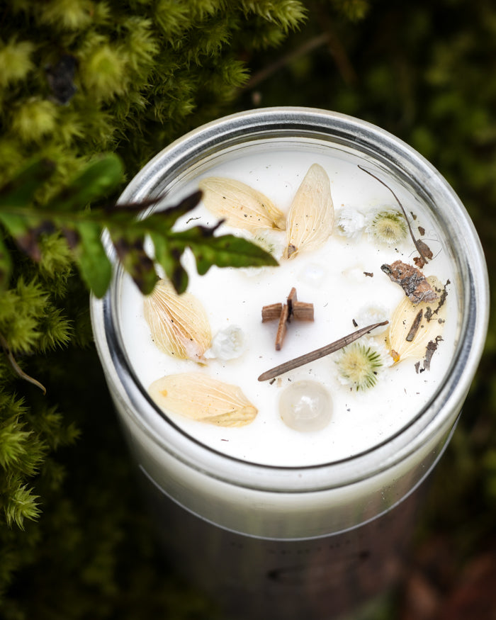 Top view of a Blessings Ritual Candle with Moonstone, Daisies & Sage by O Apothecary resting in Moss