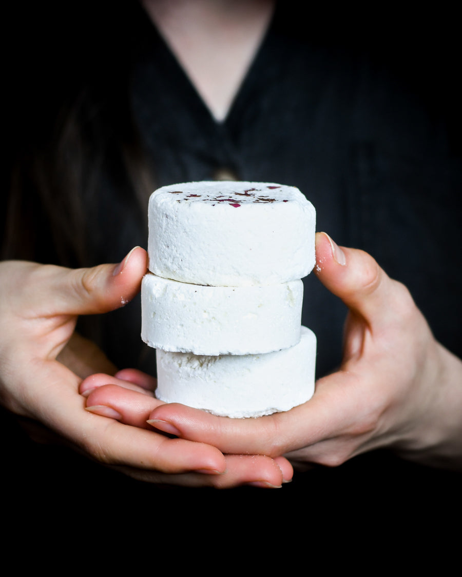 Womans hands holding a stack of handmade bath bombs by O Apothecary