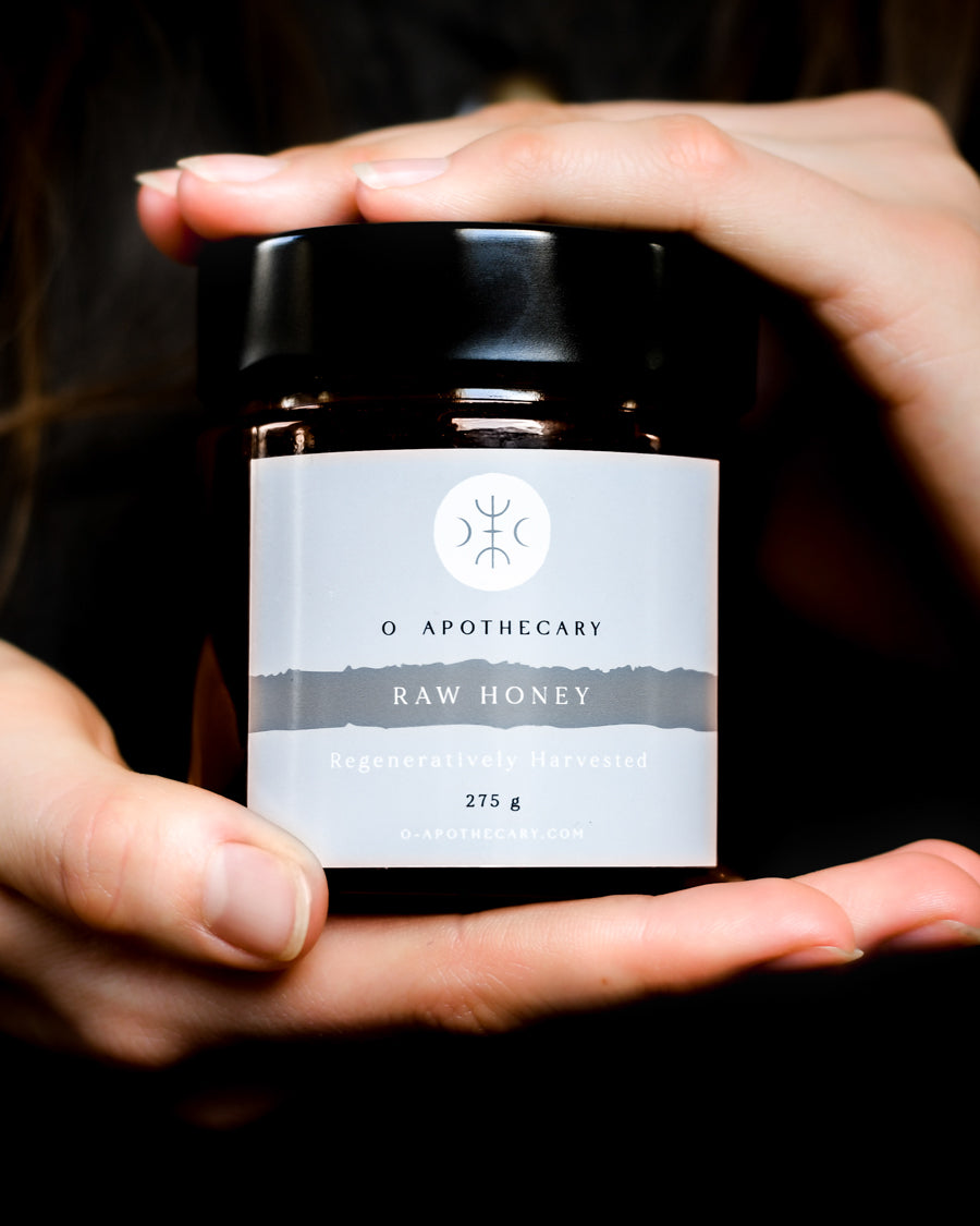 Hands holding a small jar of Raw Honey regeneratively harvested by O Apothecary