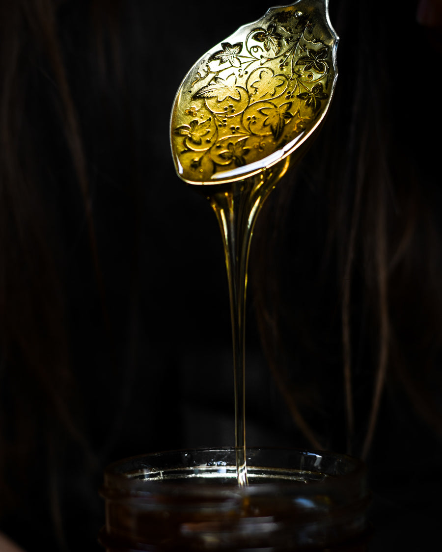 Raw honey dripping off of an antique spoon