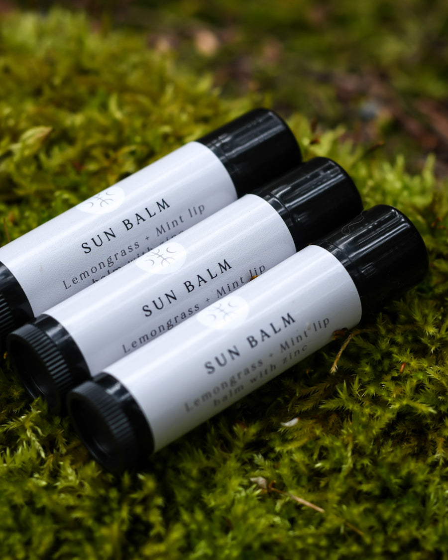 Three sun balm chapsticks resting in a patch of moss