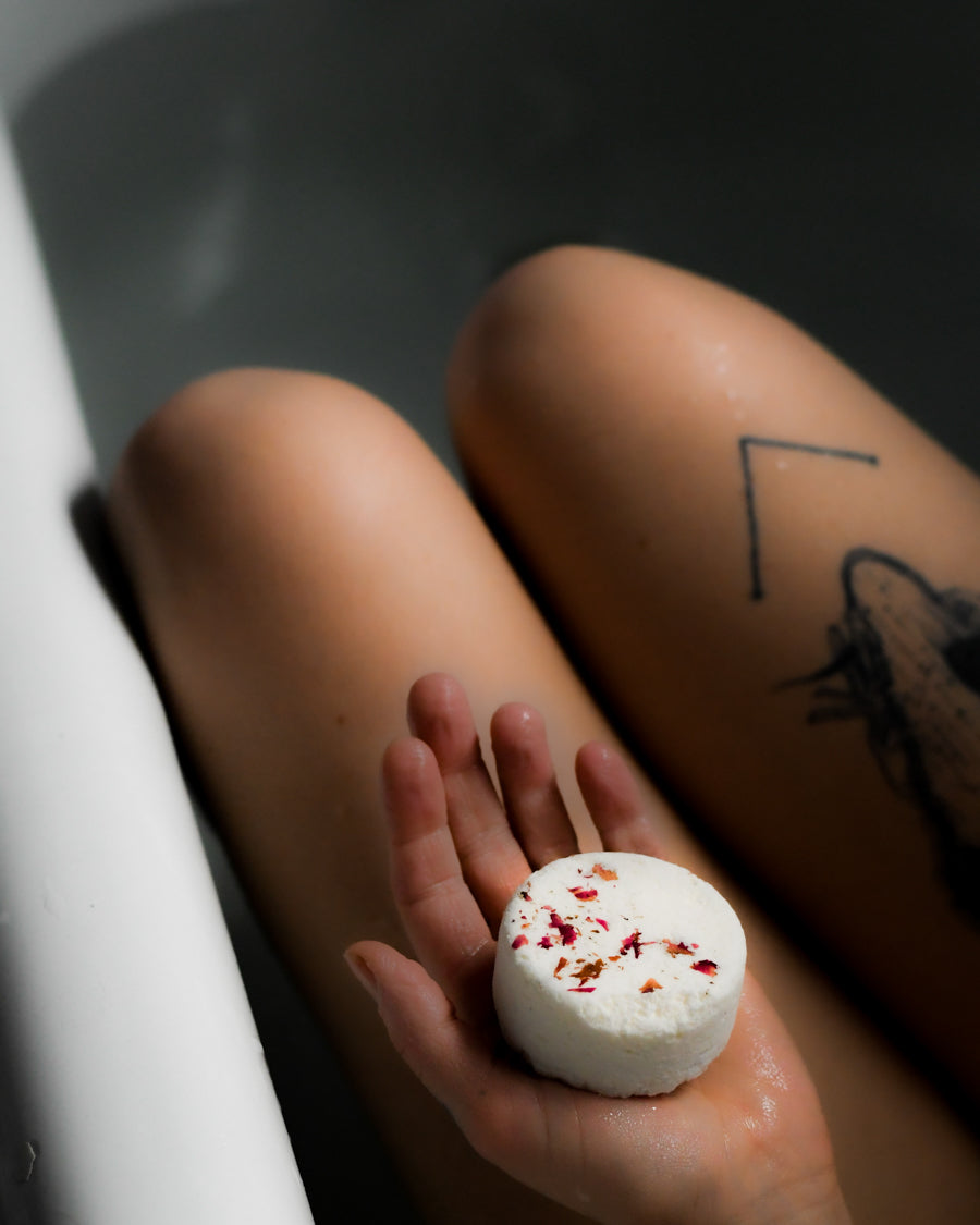 Woman in bathtub with a bath bomb in her hand