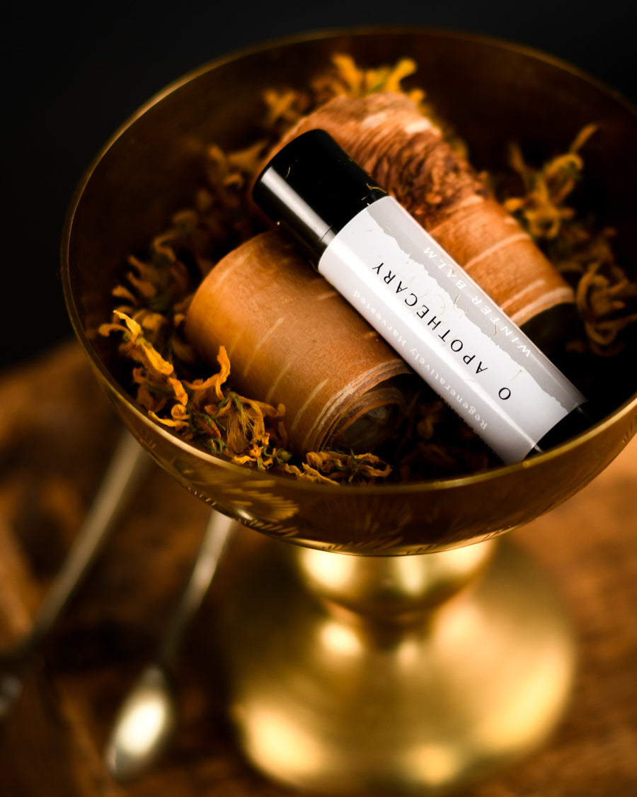 Winter balm chapstick resting in a goblet filled with saint johns wort leaves