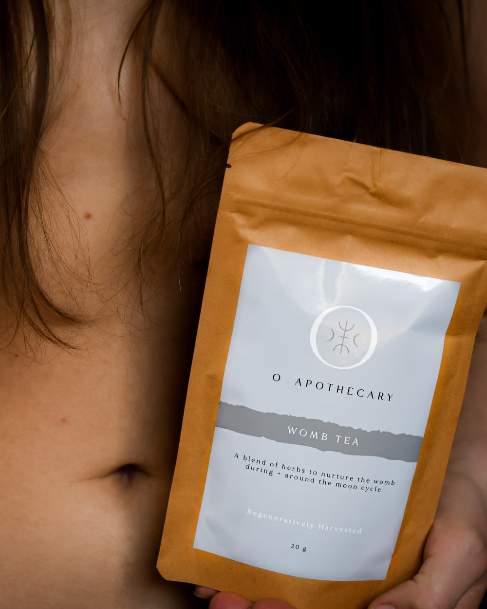 Woman holding a package of Womb Tea by O Apothecary close to her womb